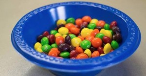 Blue plastic bowl filled with multi-colored Skittles candy