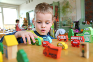 Kindergarten child plays with toy trucks on a table
